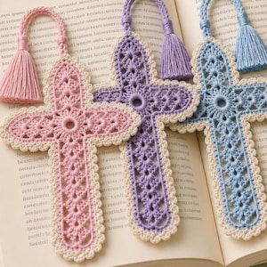 Puede incluir: Cuatro marcapáginas de ganchillo con forma de cruz en colores pastel rosa, lavanda, azul claro y verde salvia. Cada cruz presenta un intrincado patrón calado con un borde festoneado color crema y una borla de hilo a juego en el lazo superior.