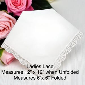 以下が含まれることがあります： 繊細なレースのトリムが付いた白いハンカチ。テキスト「Ladies Lace」が表示されています。広げた状態では30.5cm&times;30.5cm、折りたたんだ状態では15.2cm&times;15.2cmです。