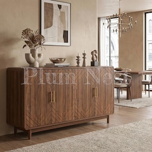 May include: A rectangular wooden sideboard with four doors featuring a geometric carved pattern and vertical gold handles. The piece stands on short tapered legs and is topped with a ceramic vase, a bowl, and decorative candle holders.