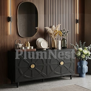 May include: A black sideboard with circular geometric door patterns and gold semi-circular handles. The top holds a tea set, stacked plates, and three vases with dried flowers. Above, an oval mirror with a gold frame hangs on a wood-slatted wall.