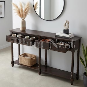 May include: A dark brown wooden console table featuring four pull-out drawers, a lower storage shelf, and turned legs. The table surface holds a beige vase with dried pampas grass, a white abstract sculpture, and stacked books.