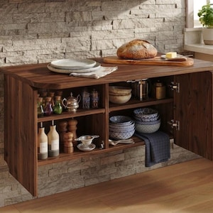 Könnte beinhalten: Ein wandmontierter Schrank aus dunklem Holz mit zwei offenen Bereichen und zwei Flügeltüren. Die Innenregale enthalten verschiedene Glasflaschen, hölzerne Pfeffermühlen, Keramikschalen mit blauen Mustern und ein Teesieb aus Metall. Ein Brot liegt obenauf.
