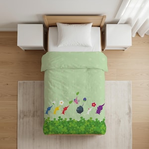 Può includere: Un copripiumino verde chiaro con un motivo ripetuto di piccoli fiori bianchi e un bordo inferiore di foglie di trifoglio verdi. Una fila di colorati personaggi Pikmin in blu, giallo, rosso, rosa, grigio, bianco e viola cammina sul trifoglio.