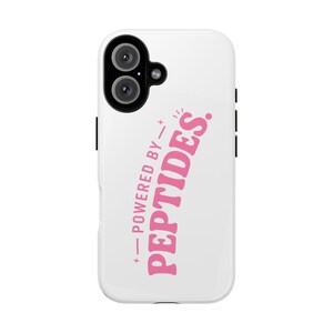 May include: A white smartphone case featuring the pink text "POWERED BY PEPTIDES." arranged vertically with small star accents. The case has a black camera cutout at the top left corner, showing two circular lenses and a small flash component.