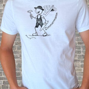 Op de afbeelding: Een wit T-shirt met korte mouwen en een zwarte grafische print van een stripfiguur met een hoed en vest, die een hamer en een zaag vasthoudt bij een dakgedeelte. De tekst "Zimmermann" en "@Roosigezeiten" is in zwarte inkt gedrukt.