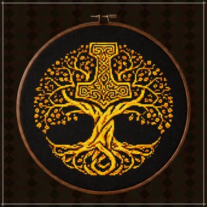 May include: A circular wooden embroidery hoop containing a cross-stitch design on black fabric. The design features a golden yellow tree with intricate roots and branches, with a large, ornate Mjolnir hammer symbol integrated into the canopy.