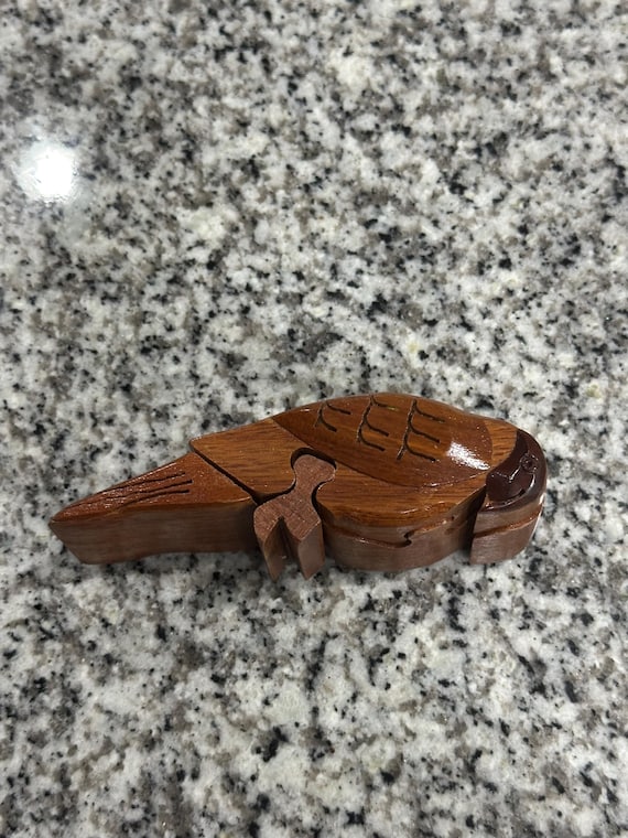 A hand-carved wooden toucan that's secretly a puzzle box — you have to solve the hidden mechanism to reveal the trinket compartment inside.