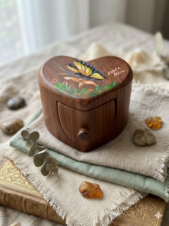 A hand-carved heart-shaped wooden puzzle box with a hidden secret drawer — the kind of tactile mystery that makes people fidget for minutes trying to crack it.