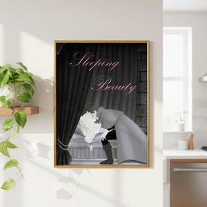 May include: A framed wall art print in a gold frame featuring a black and white illustration of a person leaning over a bed with the text Sleeping Beauty in pink script. The scene includes dark curtains and a stone wall background element.