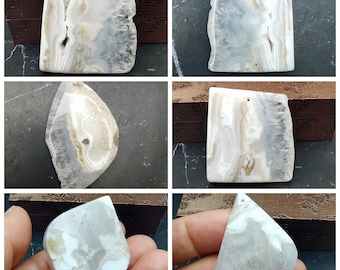 May include: Five white agate pendants with different patterns and shapes. The pendants are smooth and polished, with a natural, organic look.