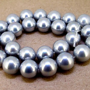 Peut inclure: Un collier de perles de culture artificielles de couleur argent. Les perles sont rondes et lisses, et elles sont enfilées sur un fil blanc.