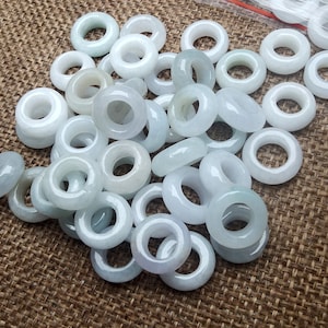 May include: A large pile of smooth, white jade rings. The rings are all the same size and shape, and they are arranged in a random pattern.