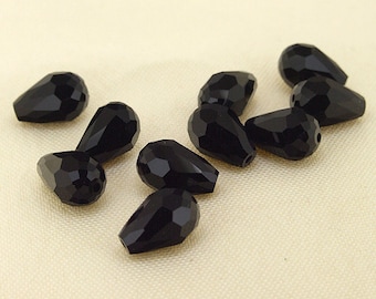 May include: A group of ten black teardrop-shaped crystal beads. The beads are faceted and have a glossy finish.