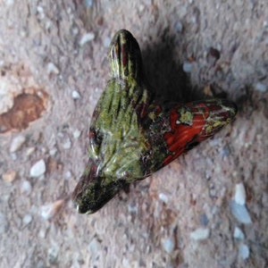 Könnte beinhalten: Grüne und rote Steinskulptur eines Fuchs Kopfes. Die Skulptur ist detailliert und hat eine glatte, polierte Oberfläche.