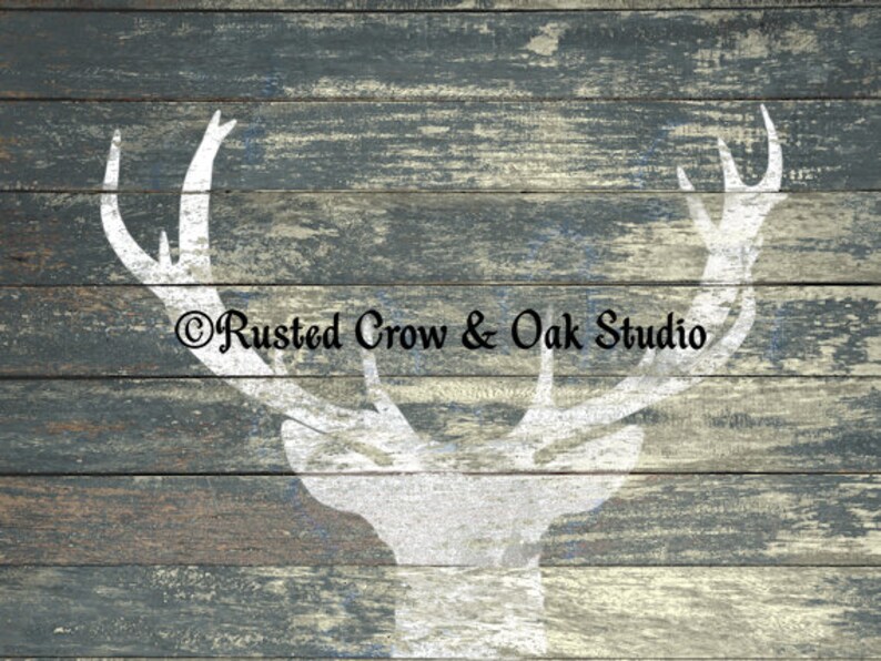 Pu&ograve; includere: Una silhouette bianca di una testa di cervo con corna su uno sfondo di legno blu e grigio invecchiato. Il testo "Rusted Crow & Oak Studio" &egrave; stampato sotto la testa di cervo.