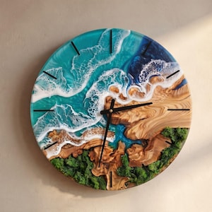 May include: A round wall clock featuring a resin ocean scene with turquoise and deep blue water, white foam waves, and natural wood grain textures. The clock face includes green moss accents along the bottom and black hands.