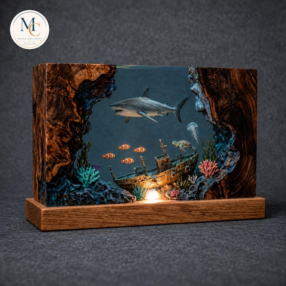 A handcrafted epoxy resin lamp with a shark suspended in glowing ocean-blue resin over a wood base — basically a bioluminescent reef on your desk.