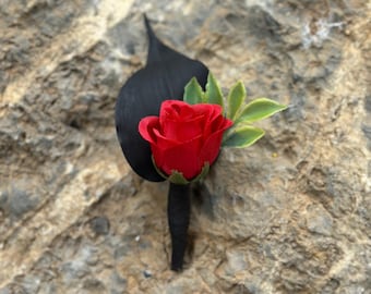 Boutonnière de rosa vermelha artificial com folhagem preta