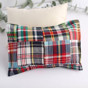 May include: A patchwork pillow with a red, blue, and green plaid pattern. The pillow is made of soft fabric and has a comfortable feel.