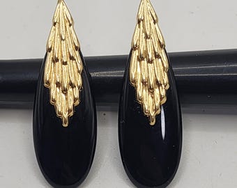 May include: A pair of teardrop-shaped earrings featuring a smooth, polished black stone base topped with a textured, gold-toned metal accent that resembles a cluster of feathers or leaves, creating a distinct contrast between the dark and metallic elements.