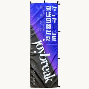 Puede incluir: Una pancarta rectangular vertical con un degradado de negro a morado y azul. Muestra el texto en blanco "joybreak", "TIMELESS SUPPLY", "ONLY ONE REAL JOY" y caracteres japoneses. La pancarta tiene pestañas de tela negra en los bordes laterales.