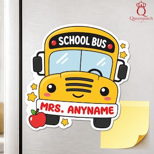 Puede incluir: Un imán de autobús escolar amarillo con cara de dibujos animados, espejos negros y una manzana roja. El texto SCHOOL BUS está impreso en negro en la parte superior, y el texto MRS. ANYNAME está en rojo sobre el parachoques blanco con estrellas.
