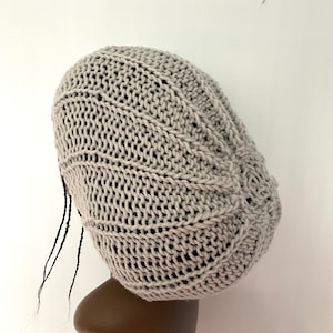 Op de afbeelding: Een grijze gebreide beanie met een uniek, gestructureerd ontwerp. De beanie heeft een losse pasvorm en is gemaakt van zacht, comfortabel garen.