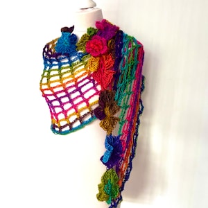 May include: A rainbow crochet shawl with colourful flower accents. The shawl is displayed on a white mannequin.
