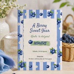 Puede incluir: Una tarjeta de invitación rectangular con fondo de rayas azules y blancas, decorada con ilustraciones de arándanos y flores blancas. El texto central dice A Berry Sweet Year, ¡Únete la dulzura!, NOMBRE, Sábado, 24 de Agosto, Dirección, Por favor, confirma antes del 15 de agosto.