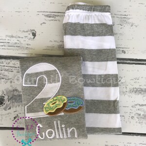 May include: Gray and white striped shirt with a large number 2, two donuts, and the name Collin embroidered on the front.