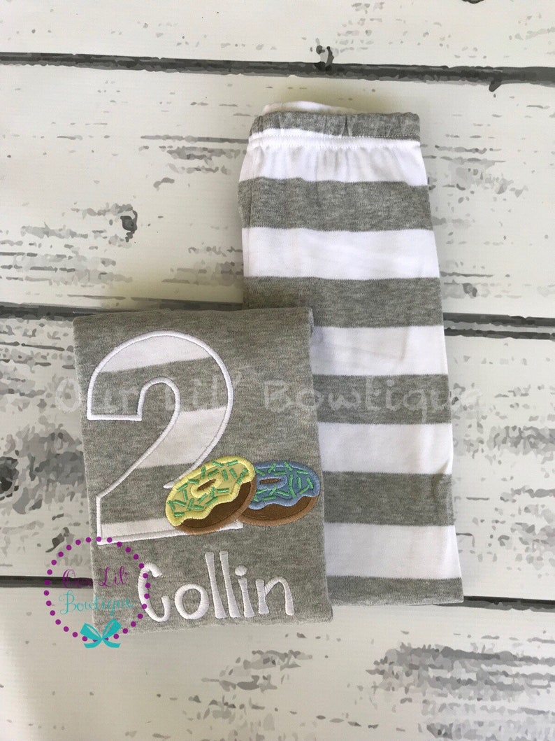May include: Gray and white striped shirt with a large number 2, two donuts, and the name Collin embroidered on the front.