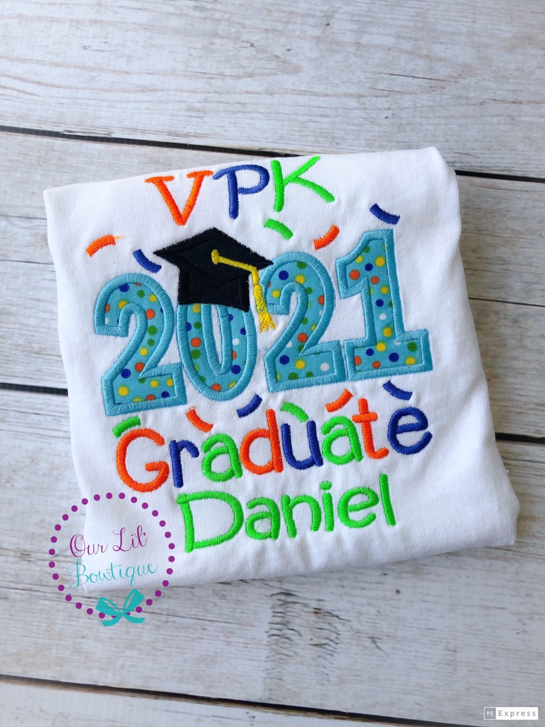 May include: White t-shirt with a blue, green, orange, and yellow embroidered design that says "VPK 2021 Graduate Daniel". A black graduation cap with a yellow tassel is above the year 2021.