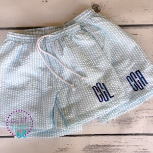 Puede incluir: Pantalones cortos de seersucker en azul claro y blanco con cintura el&aacute;stica y cord&oacute;n blanco. Los pantalones est&aacute;n bordados con las letras de monograma azul oscuro CGL en la pierna derecha. La tela presenta un patr&oacute;n de rayas texturizado.