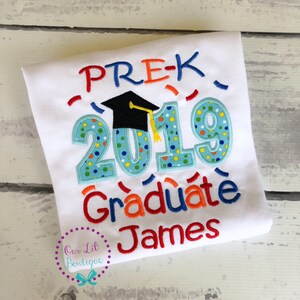 May include: White t-shirt with colorful embroidered text that reads "PRE-K 2019 Graduate James". The text is surrounded by confetti and a graduation cap.