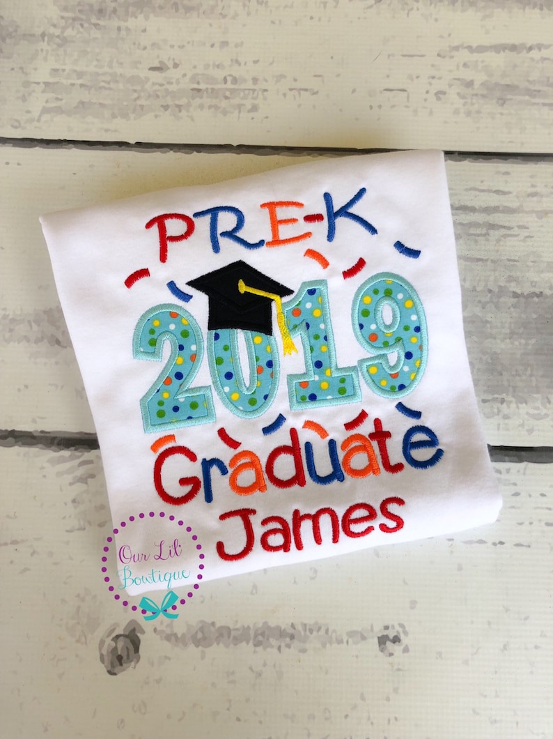 May include: White t-shirt with colorful embroidered text that reads "PRE-K 2019 Graduate James". The text is surrounded by confetti and a graduation cap.