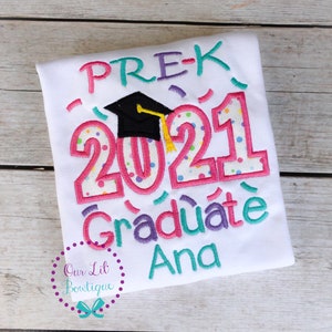 May include: White t-shirt with colorful embroidery that says "PRE-K 2021 Graduate Ana". The embroidery includes a graduation cap and confetti.