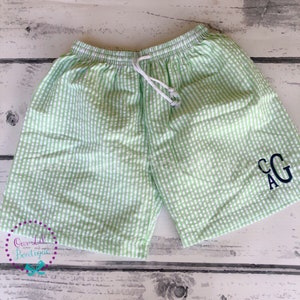 Puede incluir: Pantalones cortos de seersucker con estampado de cuadros vichy en verde claro y blanco, con cintura el&aacute;stica y cord&oacute;n blanco. La pierna derecha inferior muestra un monograma bordado en azul marino oscuro con las letras CAG en tipograf&iacute;a serif.