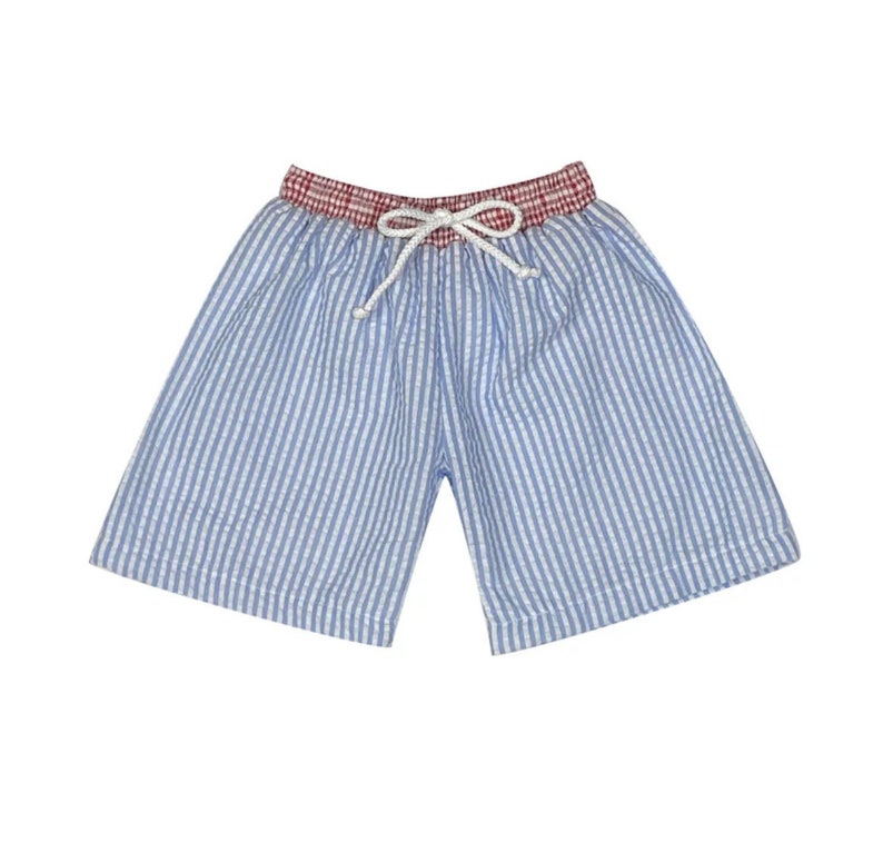 Puede incluir: Pantalones cortos de rayas verticales en azul claro y blanco con una cintura de cuadros rojos y blancos. Los pantalones incluyen un cord&oacute;n blanco atado en un lazo en la parte delantera central para ajustar la cintura el&aacute;stica.