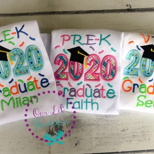 May include: Three white t-shirts with colorful embroidered designs celebrating graduation from preschool. The shirts say "Pre-K 2020 Graduate" with a graduation cap and confetti. The names Milan, Faith, and Sean are embroidered on each shirt.