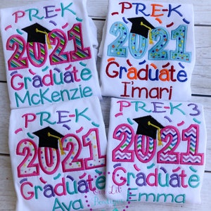 May include: Four white t-shirts with colorful embroidered designs that say "PRE-K 2021 Graduate" with a graduation cap and the names Mckenzie, Imari, Ava, and Emma.