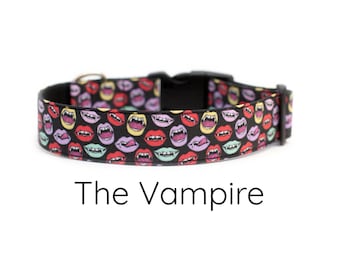 May include: Black dog collar featuring a colourful pattern of vampire fangs. The text "The Vampire" is printed below the collar.