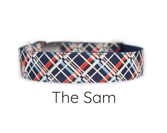 May include: A navy blue dog collar with a white, red, and blue plaid pattern. The text "The Sam" is printed below the collar.