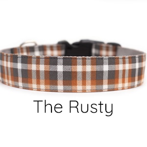 May include: A brown, gray, and white plaid dog collar with a black buckle. The collar is labeled "The Rusty".
