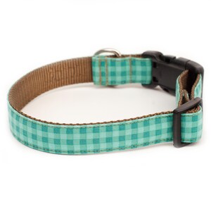 May include: A teal and brown dog collar with a checkered pattern and a black plastic buckle.