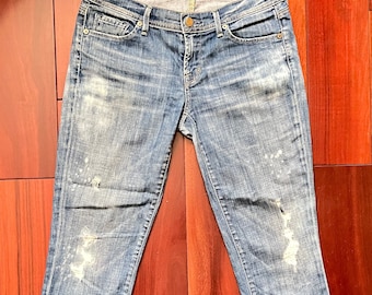 May include: Distressed light blue denim jeans with a faded look and several small rips. The jeans have a slim fit and a straight leg.