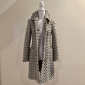 May include: A long-sleeved black and white geometric patterned coat with a collar.