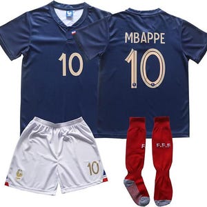 May include: A dark blue football shirt with the number 10 in gold on the front and back, featuring the name MBAPPE and number 10 on the back. Includes white shorts with a gold number 10 and a rooster emblem, plus red football socks with F.F.F text.
