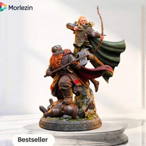 Pode incluir: Uma estatueta detalhada Morlezin apresentando um anão de barba ruiva empunhando um machado de lâmina dupla e um elfo de cabelos loiros longos mirando com arco e flecha. Os personagens estão sobre uma base rochosa com capa verde e vermelha.