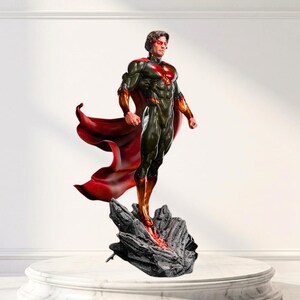 May include: A detailed figurine of a superhero standing on a jagged, dark gray rock formation. The figure wears a dark green and black armored suit with a prominent red chest emblem, red glowing eyes, and a long, flowing red cape that billows behind.