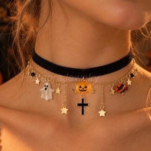 Könnte beinhalten: Eine schwarze Samt-Halskette mit einer goldfarbenen Kette und hängenden Anhängern, darunter ein weißer Geist, ein orangefarbener Kürbis, ein schwarzes Kreuz und kleine goldene Sterne, die eng am Hals anliegt.